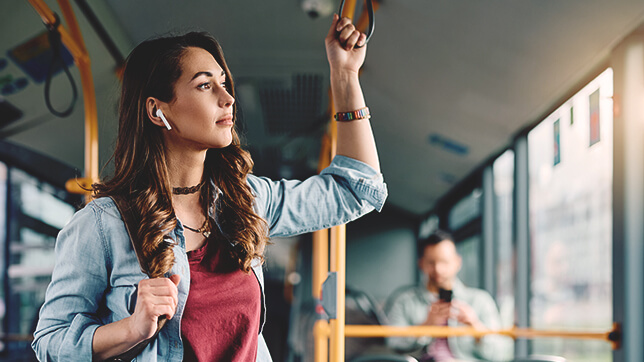 이동 중인 버스 안에서 이어폰을 끼고 창밖을 보는 한 사람